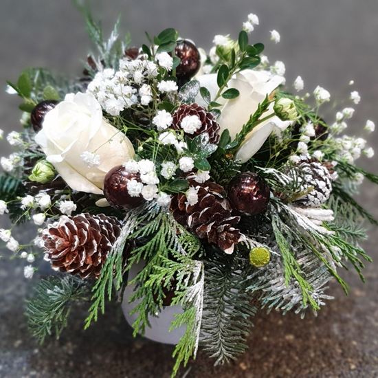 Picture of Christmas flower arrangement with white roses, chrysanthenum, pine cones and more in ceramic vase.