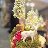 Picture of Christmas artificial arrangement with light on a wooden plate with trees and raindeer.
