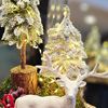 Picture of Christmas artificial arrangement with light on a wooden plate with trees and raindeer.